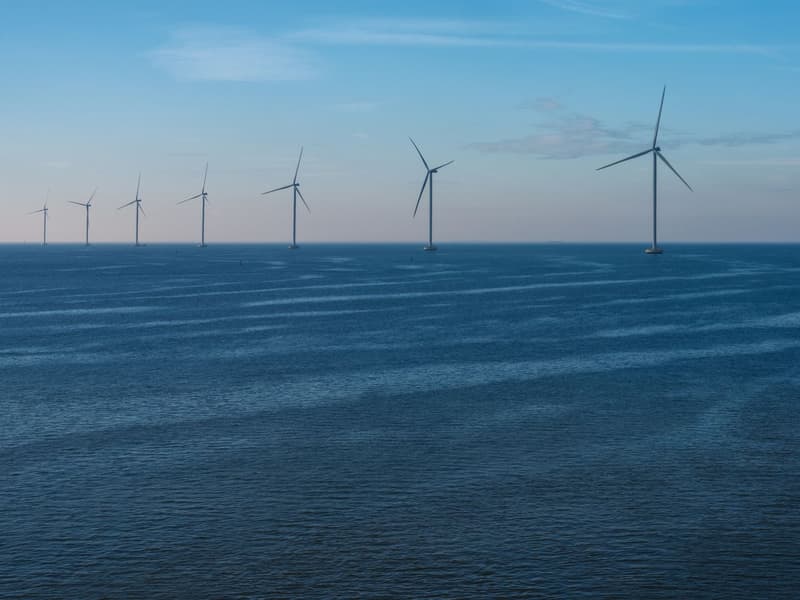 Row of offshore wind turbines standing in the sea at dusk