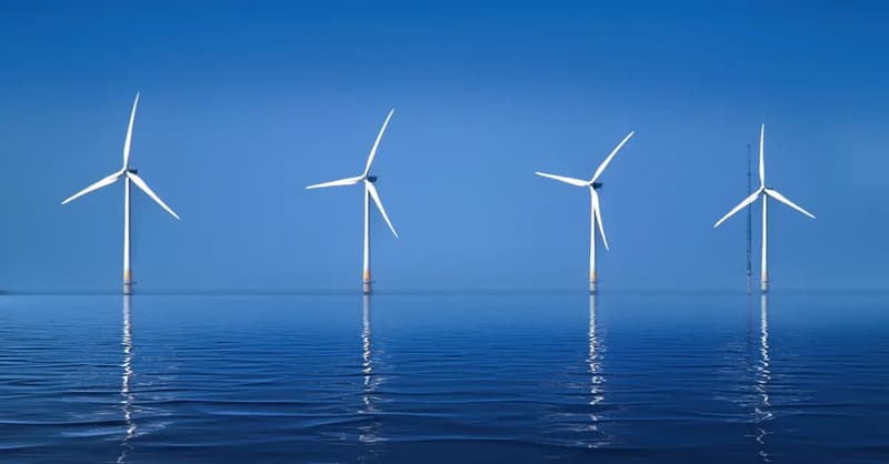 Offshore wind turbines reflected in calm blue water
