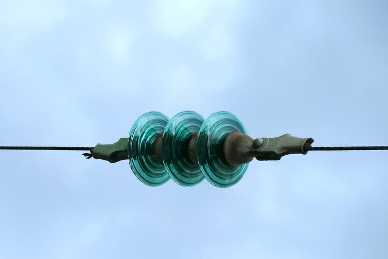 Close-up of glass insulator discs holding a high-voltage power line.