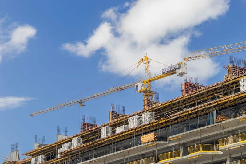 Tower cranes over a modern construction site under a clear blue sky